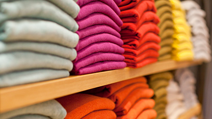 Textile et vêtements colorés en rose, jaune et orange, disposés sur une étagère en magasin
