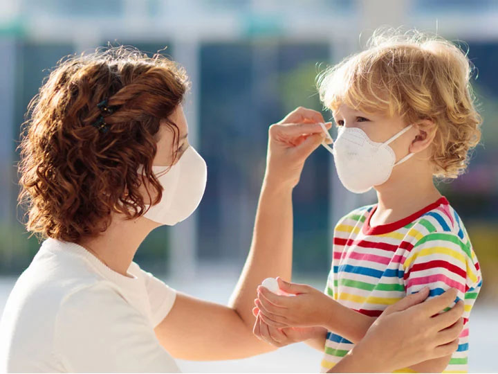 Mère portant un masque sanitaire et ajustant celui de son enfant - PPE - EPI - Equipement de protection individuelle